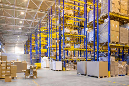 Interior of a modern warehouse storage with rows and goods boxes on high shelvesの写真素材