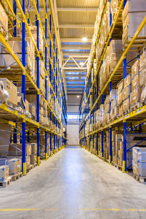 Interior of a modern warehouse storage with rows and goods boxes on high shelvesの写真素材