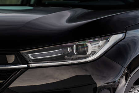 Headlight lamp of new cars. Close up detail on one of the LED headlights modern black car. Exterior closeup detail. Closeup headlights of car.の写真素材