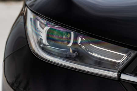 Headlight lamp of new cars. Close up detail on one of the LED headlights modern black car. Exterior closeup detail. Closeup headlights of car.の写真素材