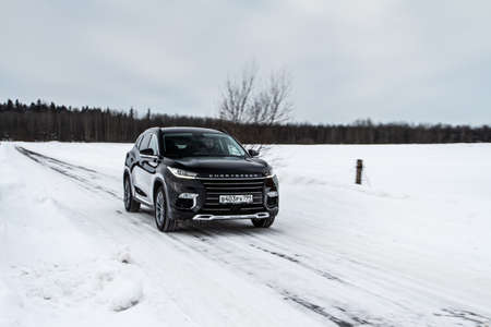 MOSCOW, RUSSIA - FEBRUARY 23, 2021 CHERYEXEED TXL SUV car in motion front side view. Black SUV on nature background produced by Chinese company. Chery Exeed TXL Compact crossover car in motion.のeditorial素材