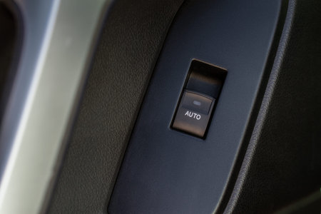 Car door handle with power window control. Dark leather interior of modern car. Dark black and...