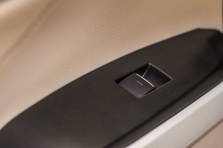 Close up view of button controlling window in modern car interior. Vehicle interior detail. Door...