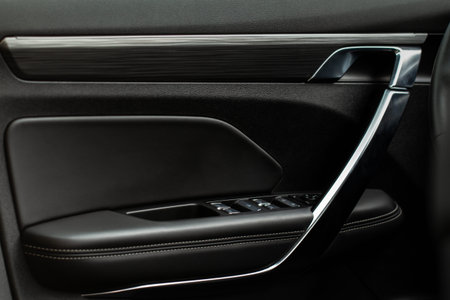 Modern car interior door handle close up. Metallic Car door opener handle inside.