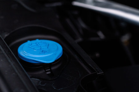 Closeup blue windshield washer fluid reservoir cap in engine room. Liquid caps inside a car engine....