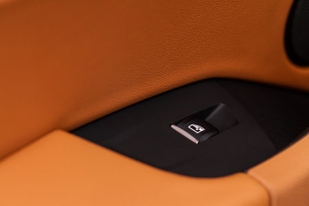 Close up view of button controlling window in modern car interior. Vehicle interior detail. Door...