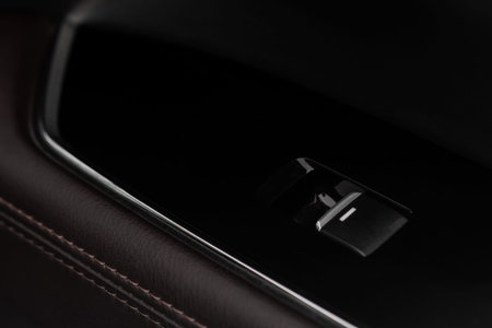 Close up view of button controlling window in modern car interior. Vehicle interior detail. Door...