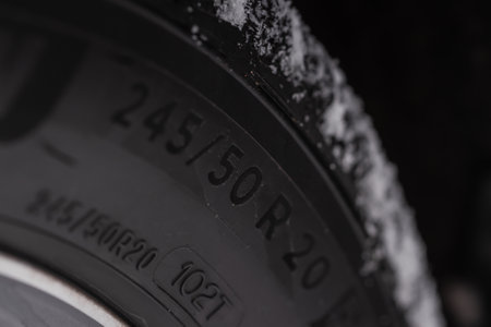 Close up view of snowy tire with tire width, height and wheel diameter designation. Winter tire size labels.の写真素材