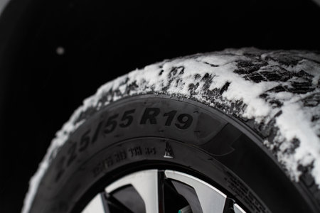 Close up view of snowy tire with tire width, height and wheel diameter designation. Winter tire size labels.の写真素材