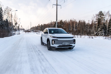 Moscow, Russia - December 25, 2021 Chery Exeed TXL car also called Vantas TX, midsize crossover car. Exterior front-side view on blurred winter background. Exeed car in motion.のeditorial素材