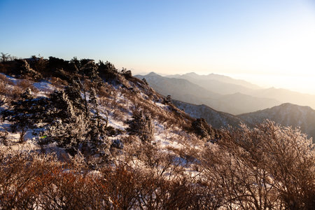 Sunrise with snow and rocks from the top of the mountain. A landscape with light and darkness along the mountain ridgeの写真素材