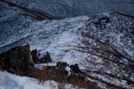 Sunrise with snow and rocks from the top of the mountain. A landscape with light and darkness along the mountain ridgeの写真素材