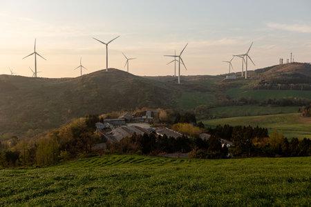 A beautiful farm with wind turbines, mountain and field sunriseの写真素材