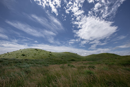 Landscape of grassy hills and blue sky with white clouds.の写真素材