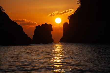 The sun rising between the lion-like rock and the rock.の写真素材