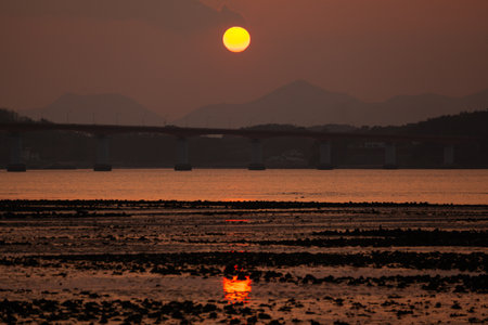 Sunset in the sea and the bridge in the background. The sun goes down.の写真素材