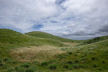 Mountain landscape with green grass and blue sky with white clouds.の写真素材