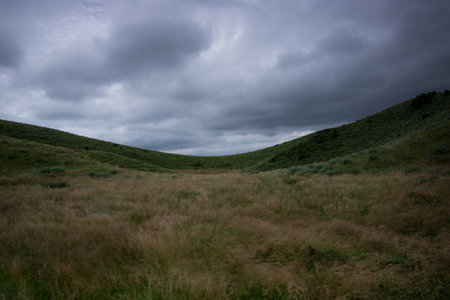 Dramatic sky over a grassy hillside in the summerの写真素材