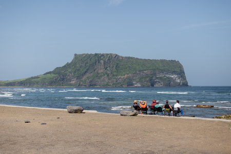 People sitting on the beach and looking at the view of the islandの写真素材