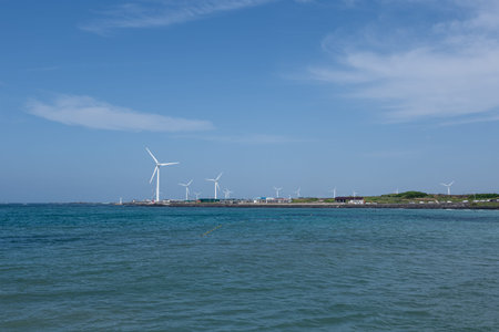 Wind turbines in the sea with blue sky and white cloud background.