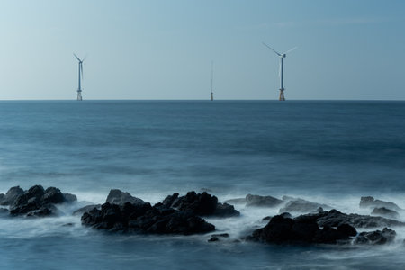Offshore wind turbines, sea exposed landscapes with crumbling waves and rocksの写真素材
