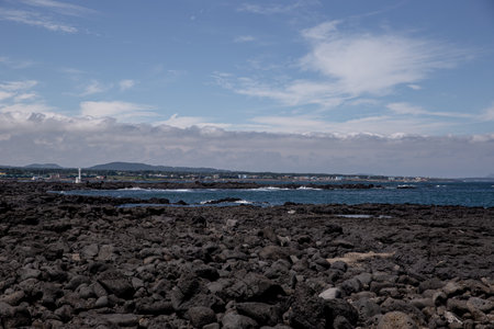 Jeju Island scenery with volcanic rock beach, blue sky, and seaの写真素材
