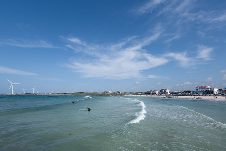 beautiful scenery with blue sky, blue sea, surfer, and wavesの写真素材