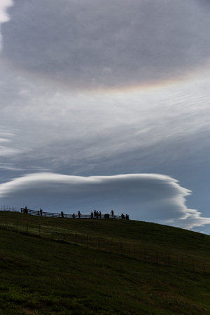 Rainbow in the sky with people silhouetted on the hill