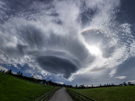 Dramatic clouds in the sky over a meadow with a footpathの写真素材