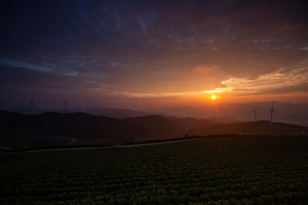 Sun rising over mountains and wind turbines, highland fields sunrise sceneの写真素材