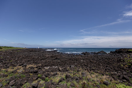 A beach scene with black volcanic rocks, blue sky and seaの写真素材