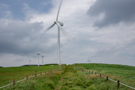 Wind turbines on a green meadow with cloudy sky in the backgroundの写真素材