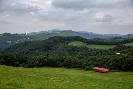 a cloudy sky background, an endless stretch of mountain ranges, and a wide pastureの写真素材