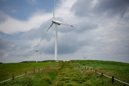 a path along cloudy skies and wind turbinesの写真素材