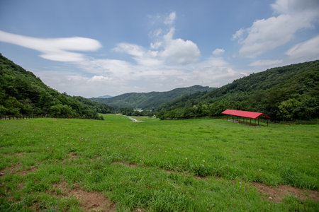 a cloudy sky background, an endless stretch of mountain ranges, and a ranch of wide pasturesの写真素材