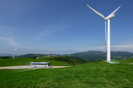 a bus that runs through clear skies, blue pastures, and wind farmsの写真素材
