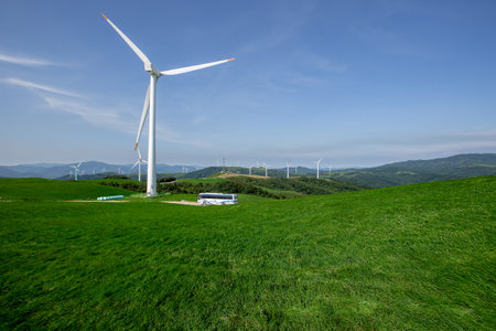 a bus that runs through clear and transparent skies, blue pastures, and wind farmsの写真素材