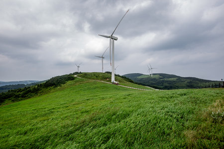 a tractor wagon that runs on a ranch with green pastures and wind turbinesの写真素材