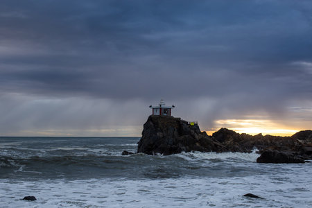Small hermitages on the rocks by the sea and a stormy sea sunriseの写真素材