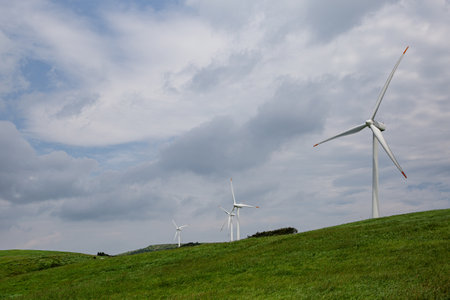 Wind Turbines on Hillside with Cloudy Sky in Backgroundの写真素材