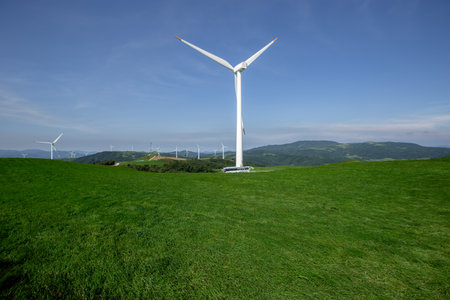 a bus that runs through clear skies, blue pastures, and wind farmsの写真素材