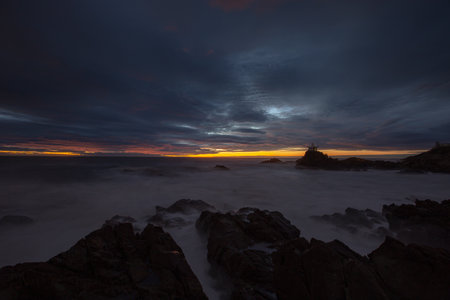 Small hermitage of rock by the rippling sea, exposed to the sea where dawn is brightの写真素材