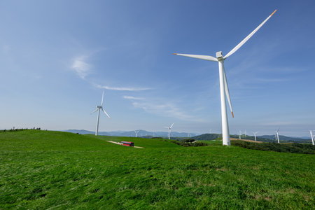 a bus that runs through clear and transparent skies, blue pastures, and wind farmsの写真素材