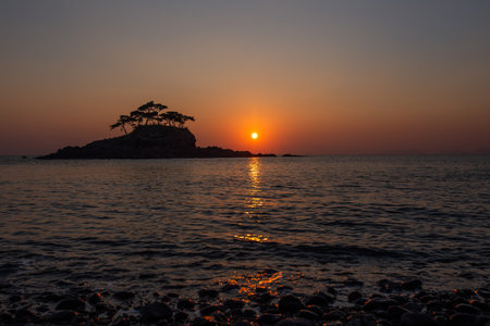 Silhouette sea sunset view of the island with pine treesの写真素材