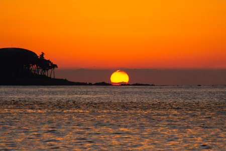 Sun and sea sunrise behind the seashore rock. Beautiful nature background.の写真素材