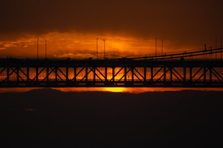 The sun rising through the clouds and cars passing through the bridgeの写真素材
