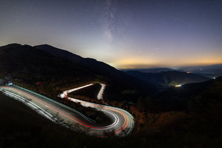 Night view of the road in the mountains with starry sky and milkyway.の写真素材