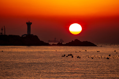 sunrise view of the sea with a lighthouseの写真素材