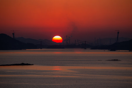 a view of a sea sunset with a silhouette of a bridgeの写真素材