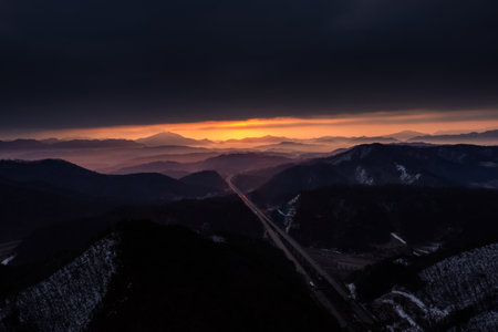 Sunrise from the top of the mountain with a road between the mountainsの写真素材